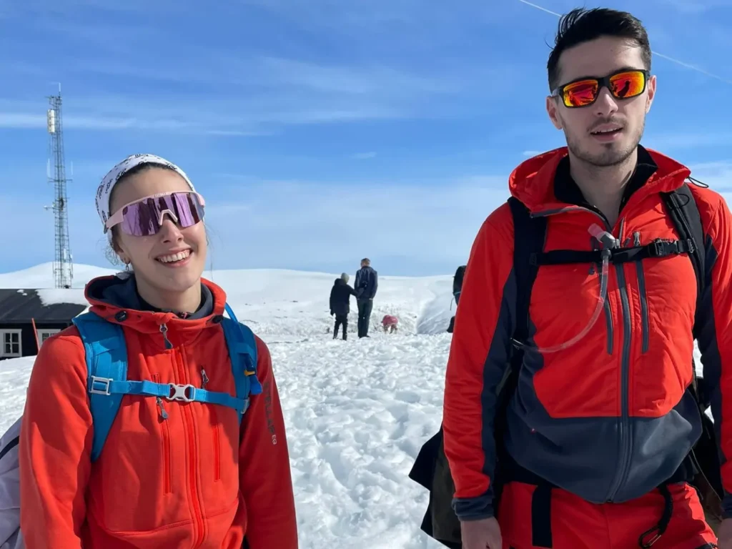 Dos personas con chaquetas rojas y gafas de sol durante una ruta por la nieve en Noruega